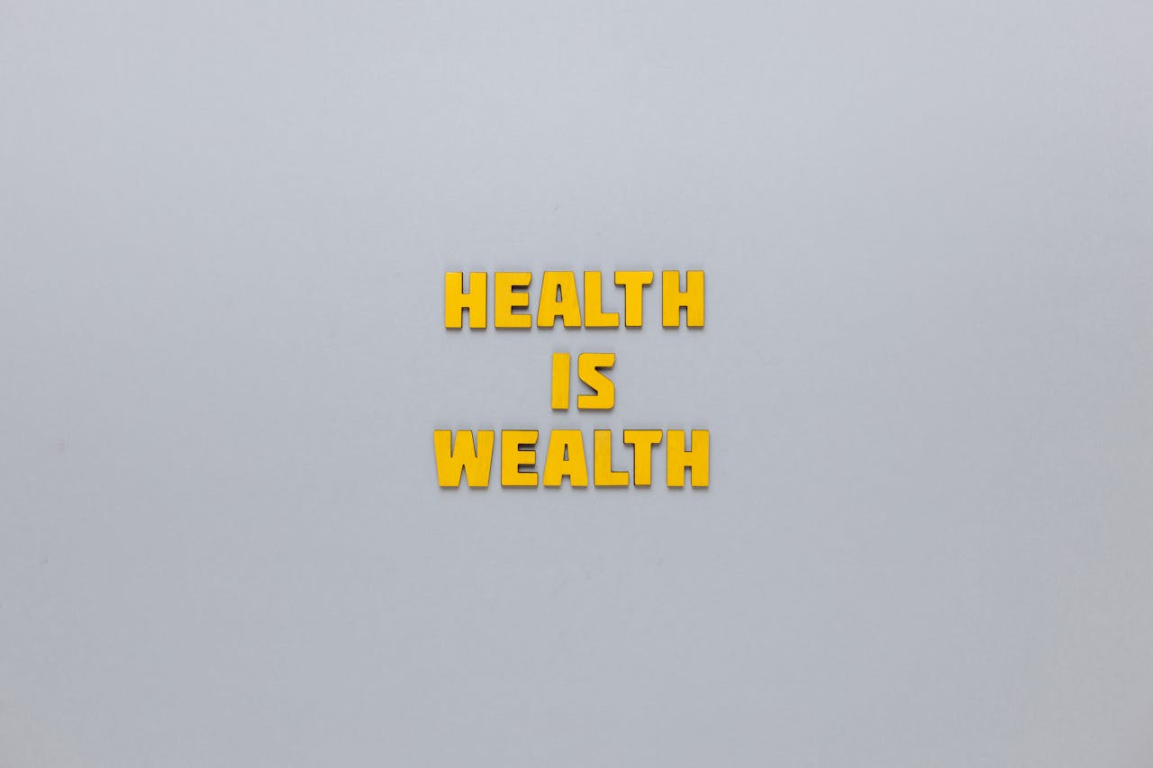 Inspirational phrase Health is Wealth in bold yellow letters on a neutral gray background.