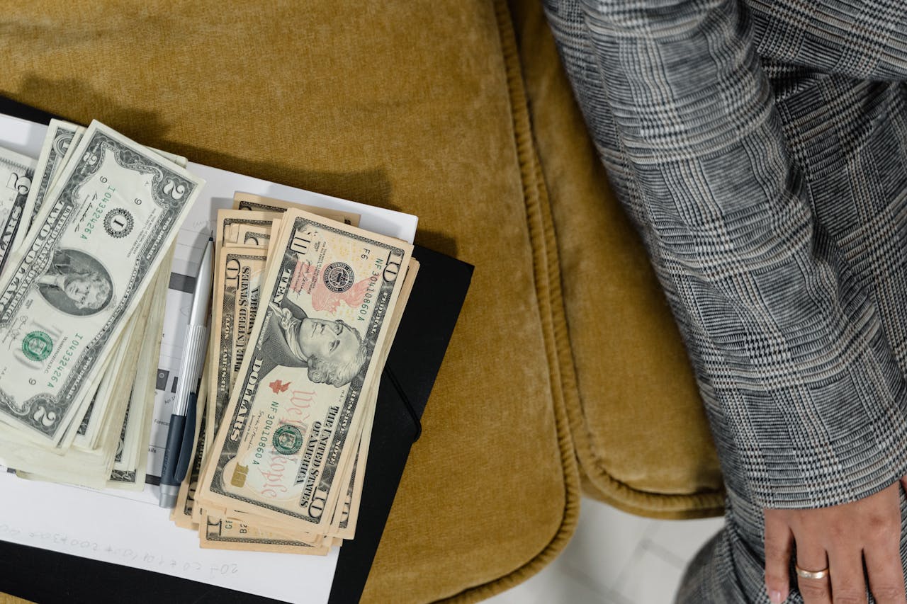 A close-up shot of US dollars on a couch, next to a plaid suit sleeve. Ideal for finance-related themes.